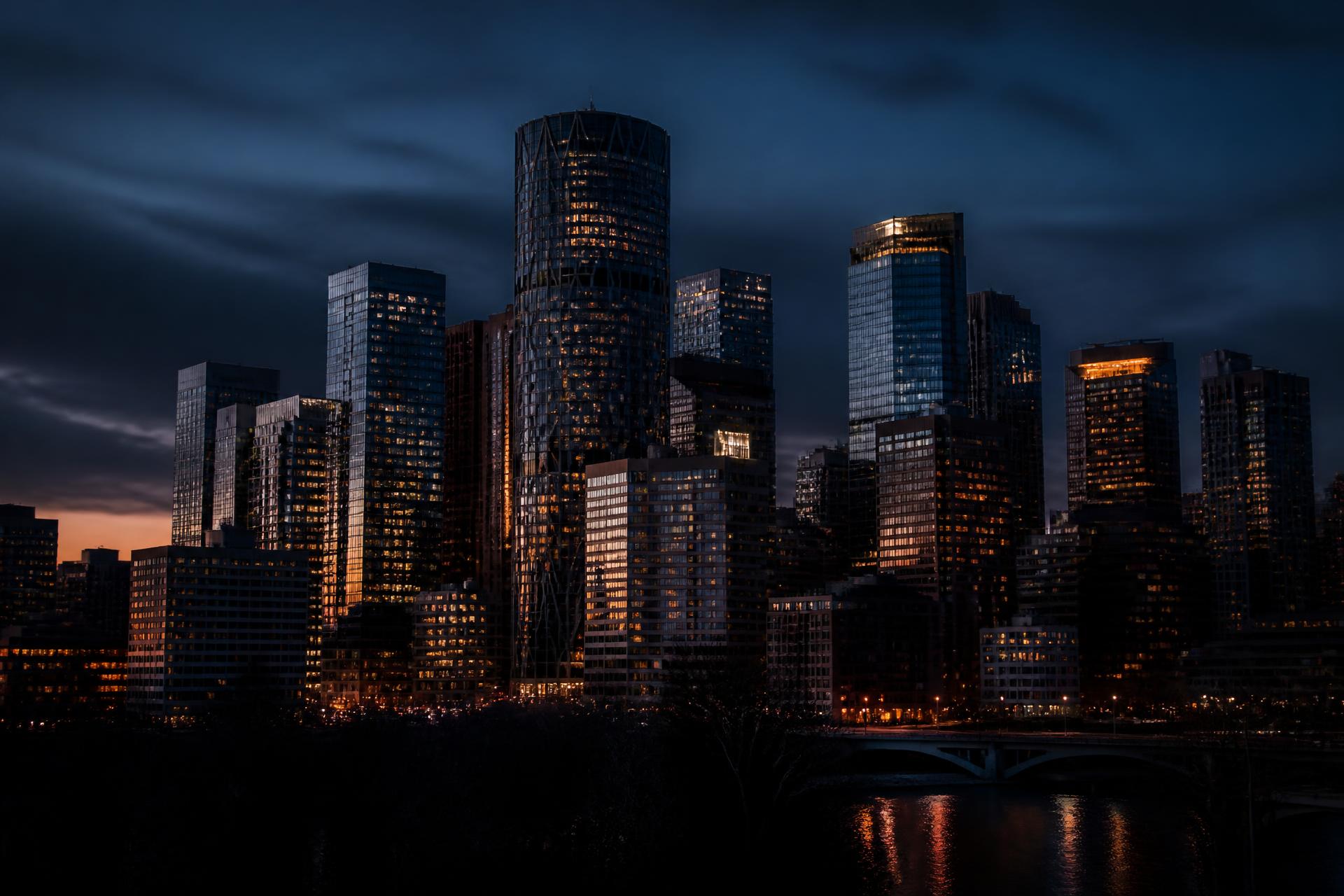 Downtown Calgary financial district skyline at dusk, glass towers lit against a deep blue sky